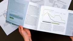 Hands holding documents with various line and bar graphs
