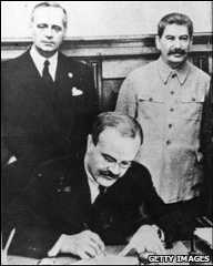 Soviet Foreign Minister Vyacheslav Molotov signs the Nazi-Soviet pact as his German counterpart Joachim Von Ribbentrop (left), and Stalin look on, Moscow, 23 August 1939