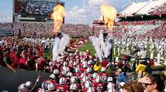 The football team running out onto the field before a game through clouds of smoke and fire in the air.