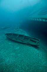 A small row boat rests next to a much larger shipwreck
