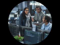 Group of IT colleagues collaborating in front of a tablet and a computer