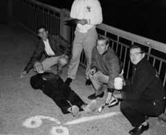 A black and white photo of five students on the Harvard Bridge, with Oliver Smoot lying on the ground.