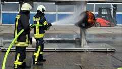 Zwei Feuerwehrleute spritzen Wasser auf eine brennende Turbine