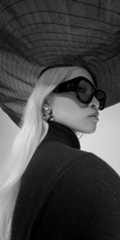 Close-up black and white photo of person in sunglasses and large hat