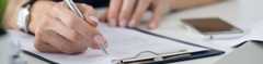 Close up of someone signing a paper on a clipboard