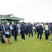 Players and caddies gather on the course, awaiting further instructions after play is suspended during day three of the 2025 Alfred Dunhill Links Championship