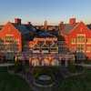 The grand red brick Dolan Center glows golden in the setting sun, with a wide lawn and patio for students to enjoy.