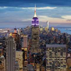 NYC skyline with empire state building lit up with purple lights