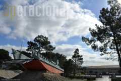 Ao fundo o edificio de comando da Base de Fuzileiros e em primeiro plano uma Lancha de Desembarque Média, «Homenagem da Marinha a todos os marinheiros que em África (1961-1974) serviram nas lanchas de desembarque... ...em condições particularmente dificeis, o que muito honrou a Armada e o País»  -