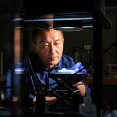 Two men wearing glasses examine a device in the University of Rochester Lab, showcasing collaboration and innovation.
