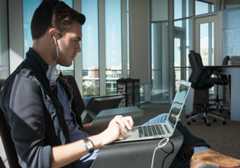 Student working on a laptop wearing earbuds. 