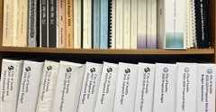 Binders on a bookshelf containing City of Seattle budget books from the 1990s through 2024