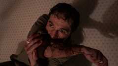 Blake (Christopher Abbott) sucks blood out of his wounded arm in Wolf Man (2025).