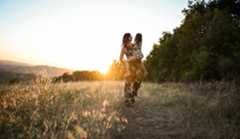 family-2 A photo of a woman carrying a young girl in a field of dried grass.