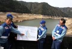 常時満水位から41㍍下がっていると説明する松岡課長㊧＝新城市川合の宇連ダムで