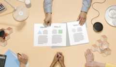 An image of a person showing three pieces of paper to a group of people. The papers say "Idea 1," "Idea 2," and "Idea 3."