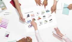 Multiple hands pointing to a piece of paper with images under review