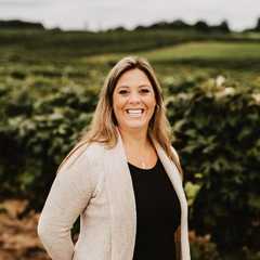 Nancie Oxley stands in grape field at vineyard.