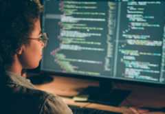 Back behind view photo of programmer looking at big monitor