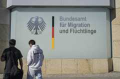 Zwei Männer gehen an einer Außenfassade mit dem Bundesadler und dem Schriftzug Bundesamt für Migration und Flüchtlinge entlang. Symbolfoto zu Migration und Asylverfahren in Deutschland. Vor dem Bundesamt für Migration und Flüchtlinge: Fast eine Million abgelehnte Asylbewerber in Deutschland. Foto: picture alliance / Joko | Joko