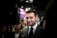 Mit schwarzem Jackett und schwarzer Krawatte grinst er in die Kamera: Der Vorsitzende des Rassemblement Nationa, Jordan Bardella