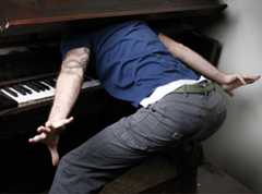 Man with head stuck in piano cover