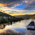 Beautiful vibrant sunset view of the river Moselle at the small wine growing town Zell (an der Mosel) with hills full of grape vines with a barge on the river