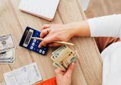 Person Holding Money while working on Calculator
