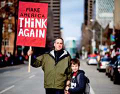 Father and Son in Street Holding up a Sign