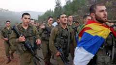 A newly-recruited Israeli paratrooper draped in the Druze flag marches with others in full combat gear on a 50-kilometer 12-hour hike in the mountains near Jerusalem on November 10, 2022.