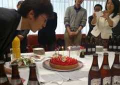サプライズのお祝いケーキのろうそくを吹き消す中野社長