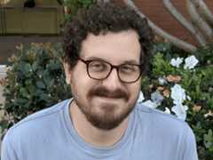 A man with glasses and a beard smiling into the camera