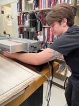 Luke Ayers uses the board slotting machine in General Collections Conservation.