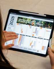 Persoon bekijkt internationale vakantiekalender 2025 van Brabant Partners op tablet met koffie in hand.