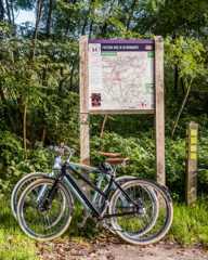 Twee fietsen geparkeerd bij knooppuntenkaart voor fietsroutes in een Brabants bosgebied.