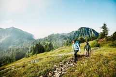 Daughter leading father on morning hike up mountainside