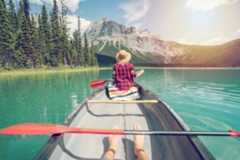 Pov of couple paddling red canoe on turquoise lake