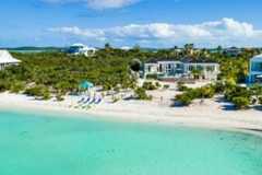 House among coastal vegetation next to sandy beach