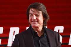 Tom Cruise trägt einen Anzug und lächelt.