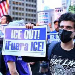 A protestor holds a sign that says "ICE OUT!"