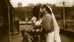 A vintage sepia-toned image of two women embracing.