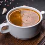 Bone Broth in a two-handled mug on a cutting board