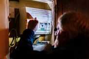 Senior man checking home fuse box by torchlight during power outage