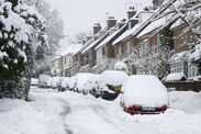 Parked cars in residential street covered in thick snow after blizzard.
