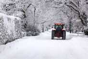 Tractor driving down a snow covered road