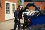 Stock image of a man opening a car boot.