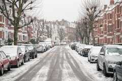 Met Office issues fresh snow warning as flooding expected in 75 areas - full list A terraced street with parked cars on two sides, covered in winter snow
