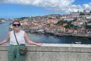 Julie stands in front of a waterfront view of Porto