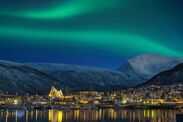 View at night on illuminated Tromso city with cathedral and majestic aurora borealis