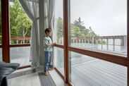 Boy stands at the window and looks at the rain.